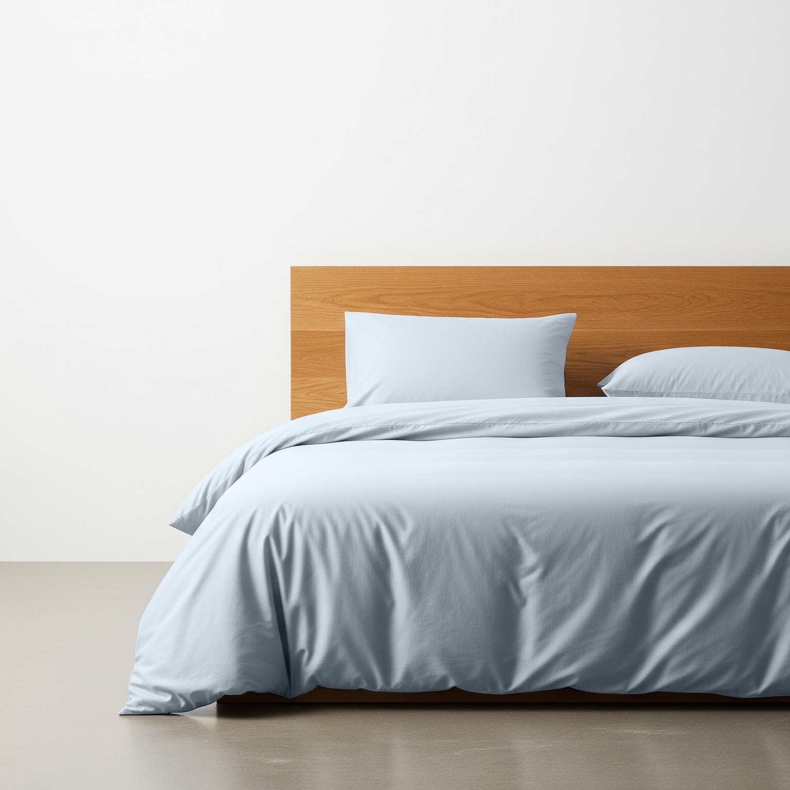 Bed with wooden headboard and gray bedding against a white wall